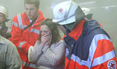 Foto: Zwei Helfer kümmern sich um eine Frau, die schockiert an einem Einsatzort steht.